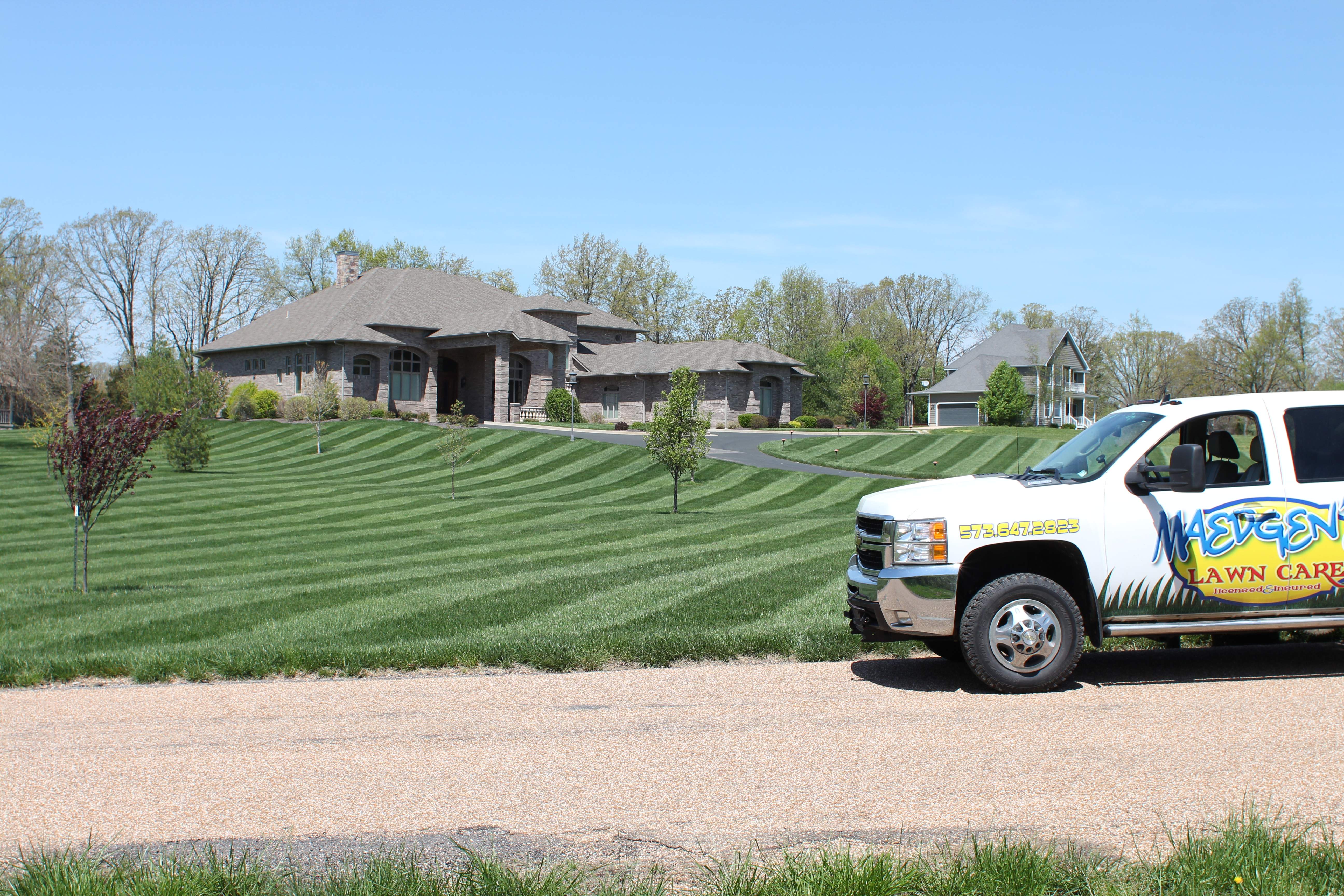Maedgen's branded truck parked beside a perfectly striped estate lawn