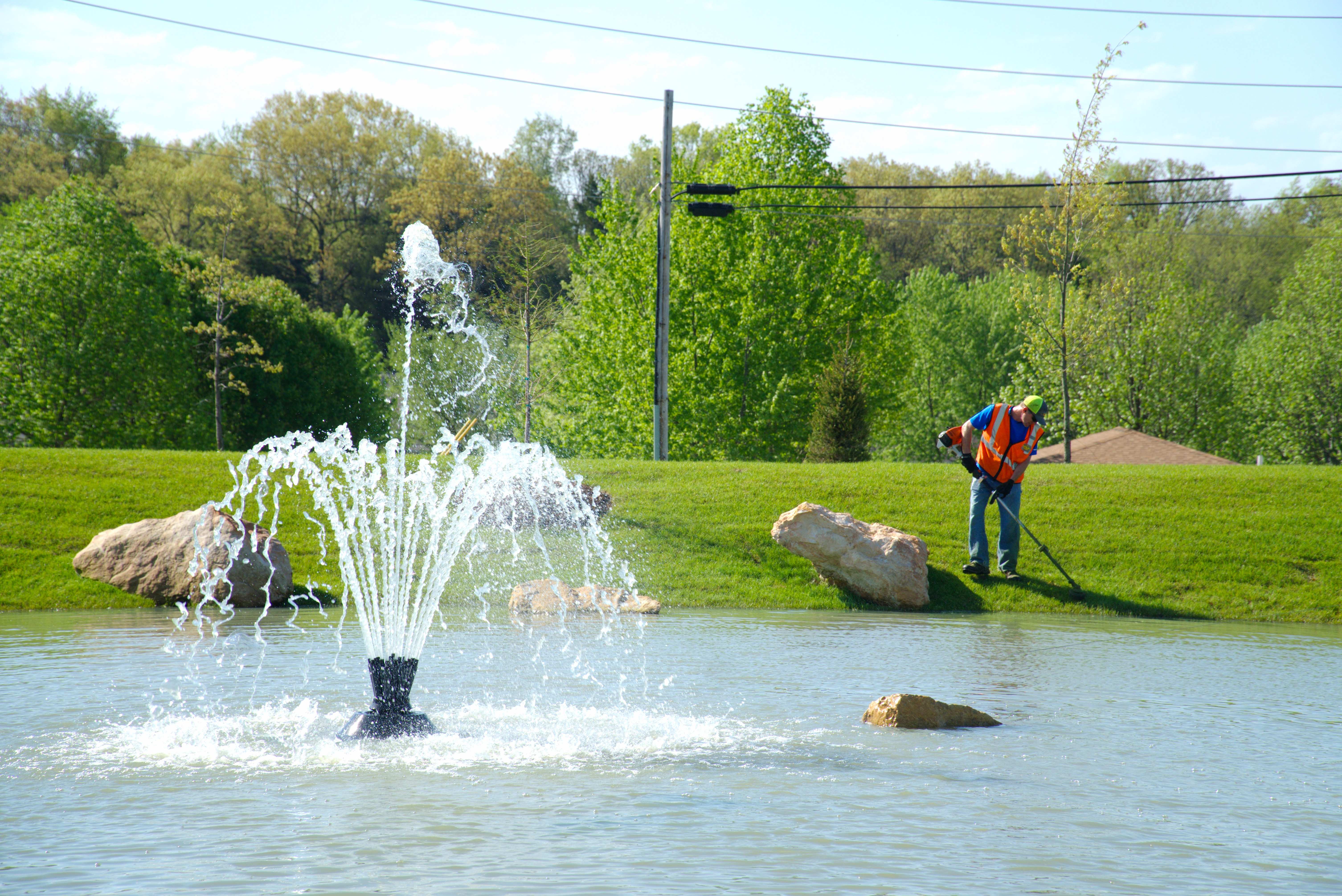 Crew performing detail trimming around a commercial water feature