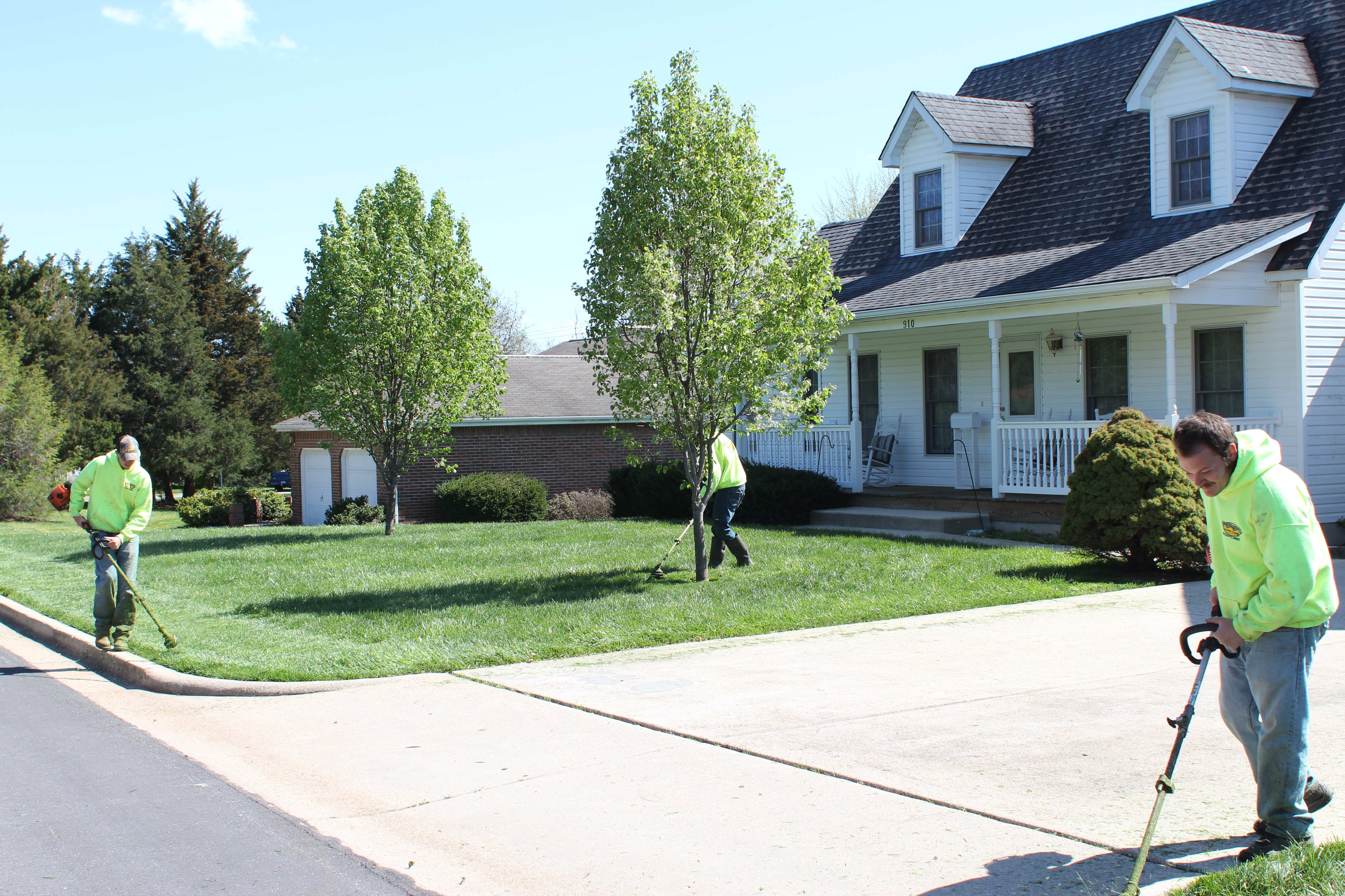 Three crew members trimming and edging a residential property